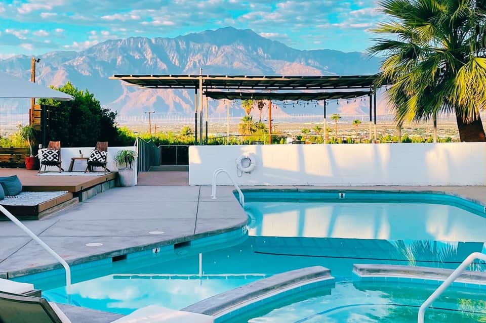 Resort pool with mountain backdrop, lounge seating, and modern pergola structure