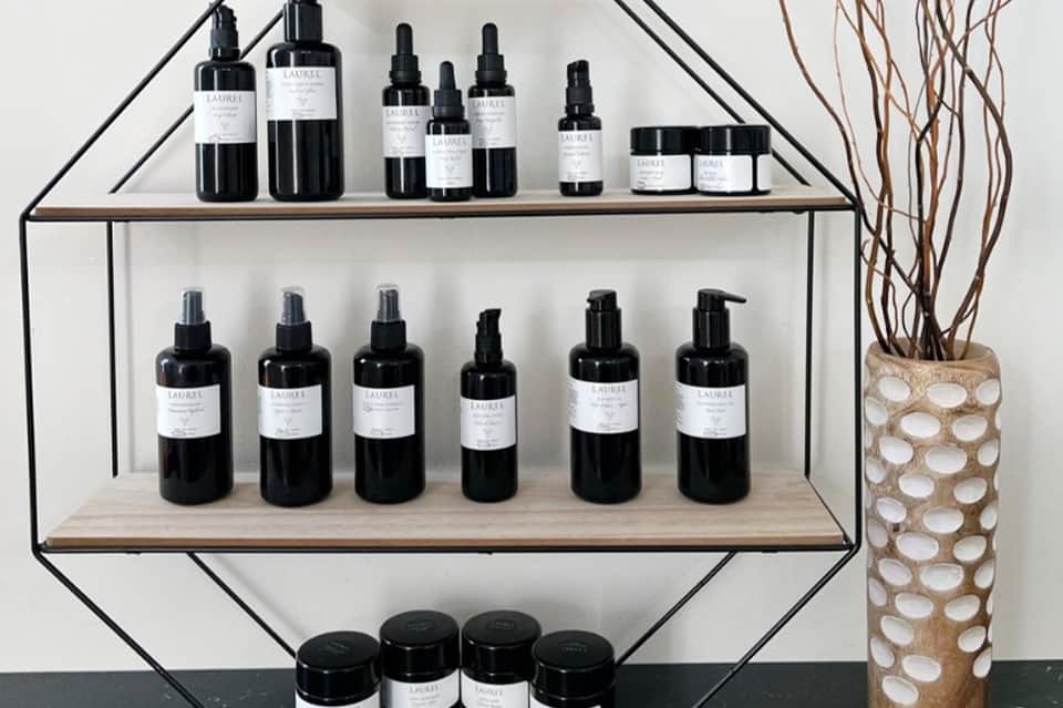Shelving unit displaying black bottles of skincare serums and creams with white labels