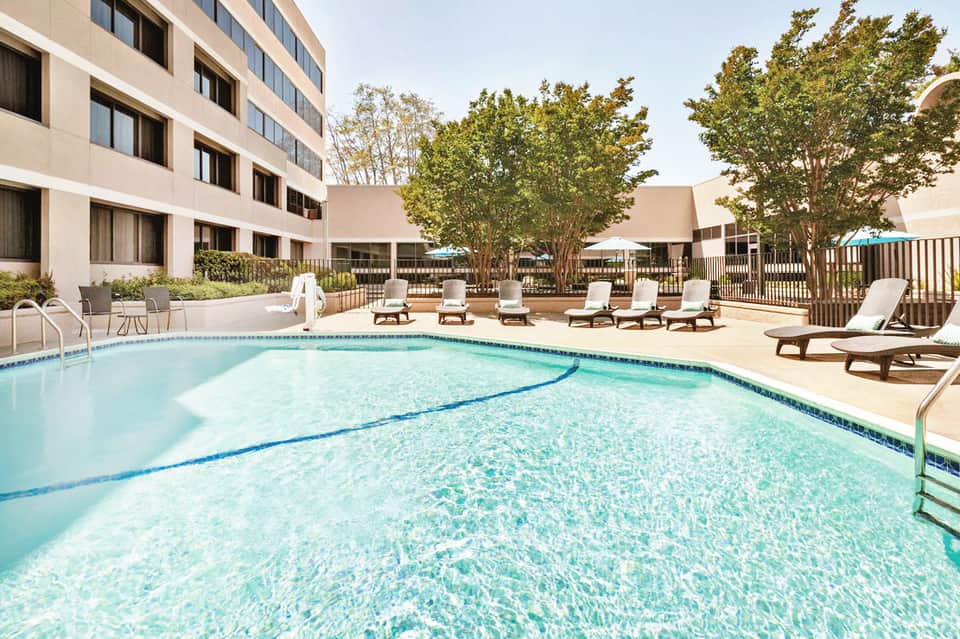 Resort pool with lane markers surrounded by lounge chairs and modern buildings