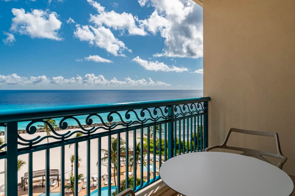Oceanfront balcony with turquoise railing overlooking blue water and white sand beach