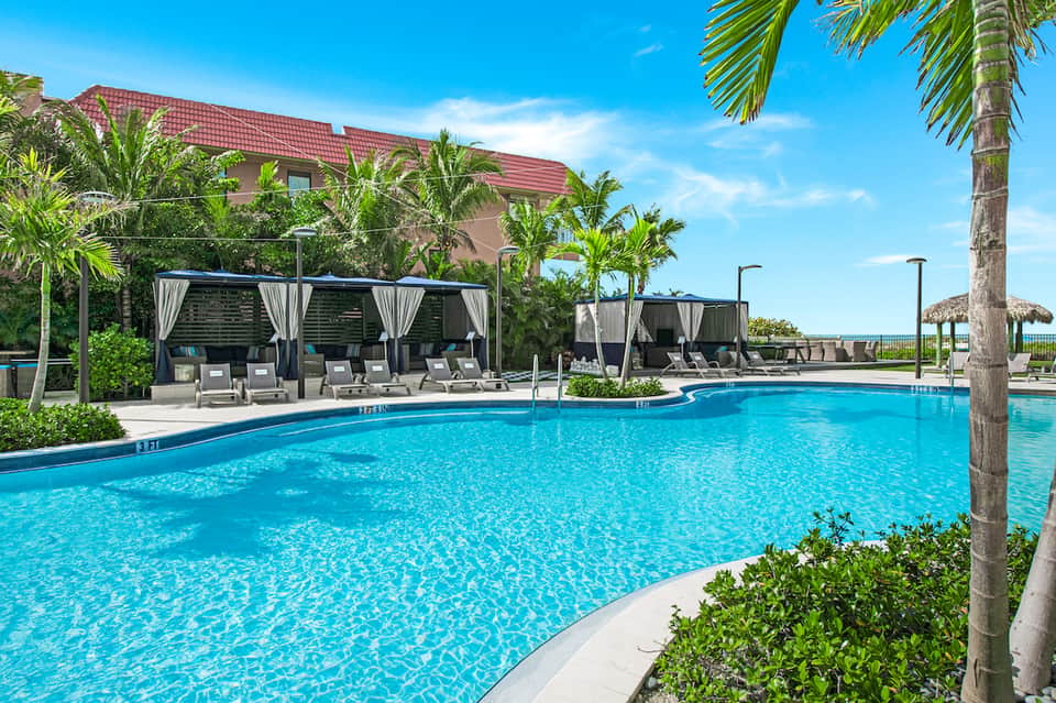 Resort pool with cabanas, palm trees, and tropical landscaping