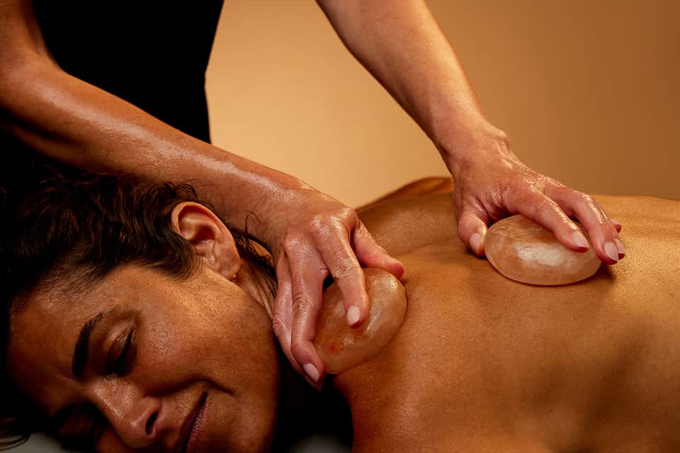 Hot stone massage therapy treatment on person's back
