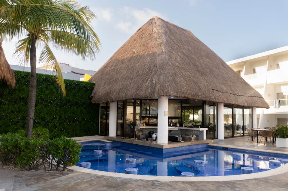 Thatched-roof poolside cabana with white columns and blue resort pool
