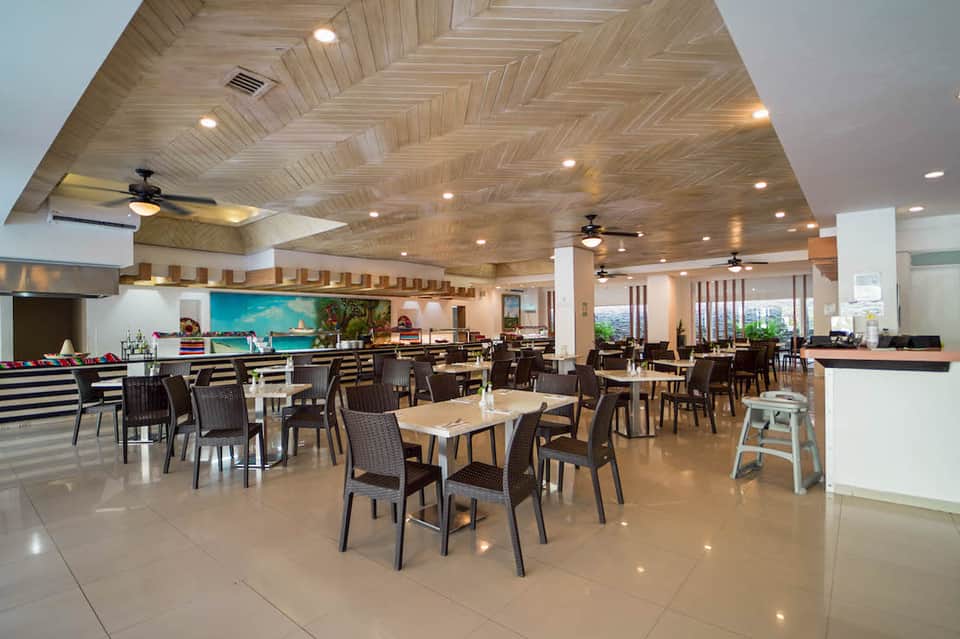Spacious resort dining area with herringbone wood ceiling, black chairs, and turquoise accent wall