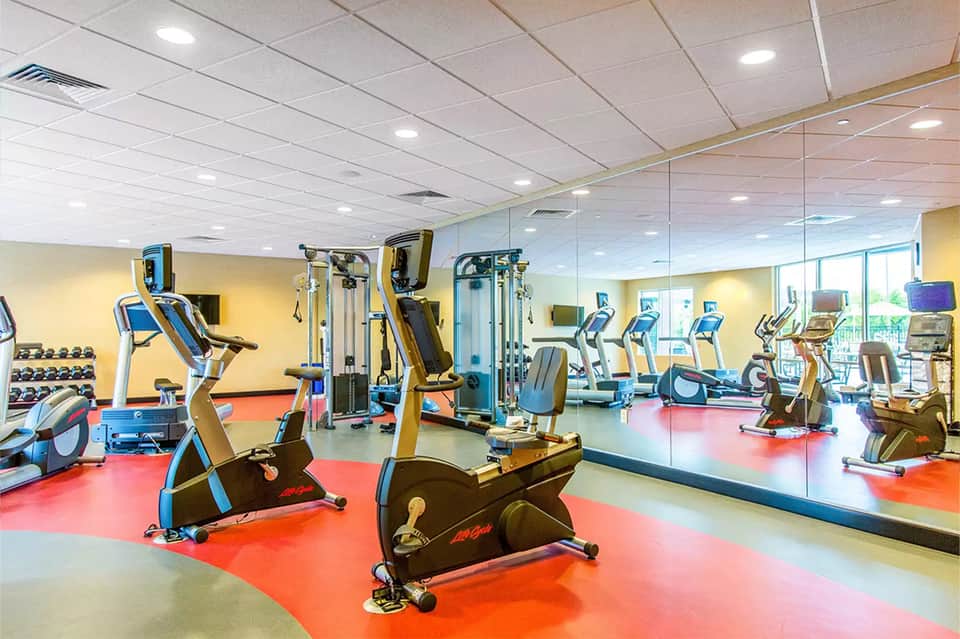 Fitness center with colorful floor, exercise bikes, weight equipment, and full-length mirror