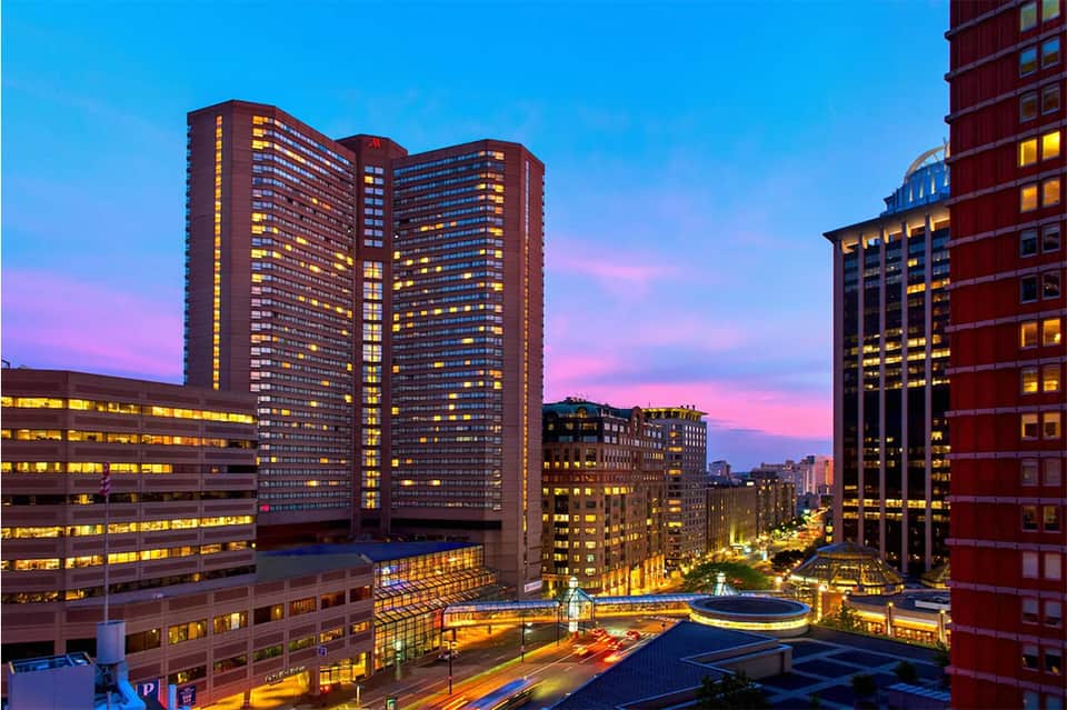 Urban cityscape at dusk with illuminated high-rise buildings and glowing street lights under purple sky