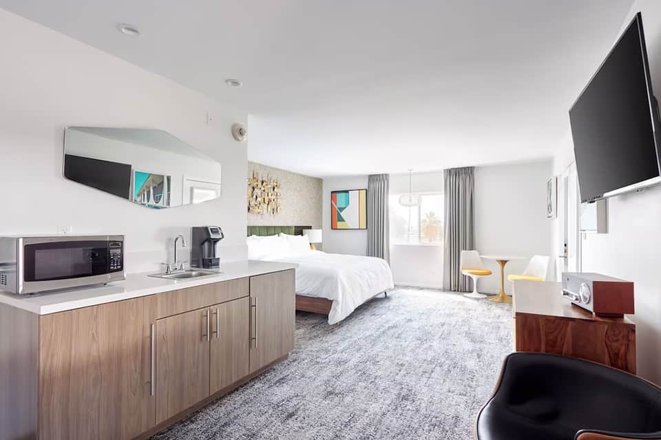 Spacious hotel suite with kitchenette, king bed, sitting area, and modern furnishings