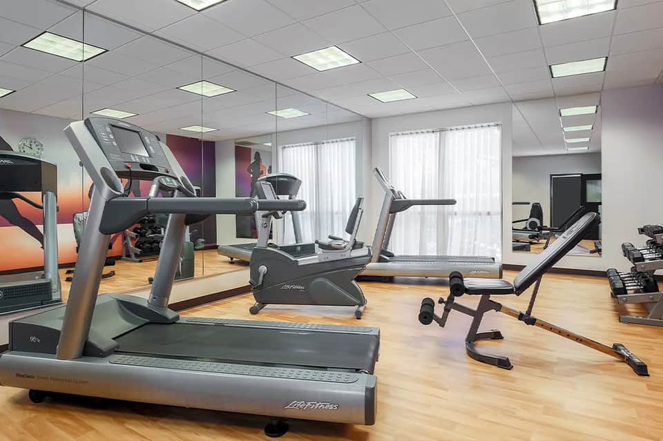 Contemporary gym with treadmills, exercise bikes, weight equipment, and mirrored walls