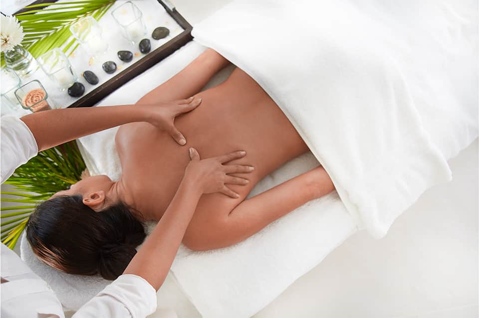 Woman receiving hot stone massage treatment at spa with calm, serene setting