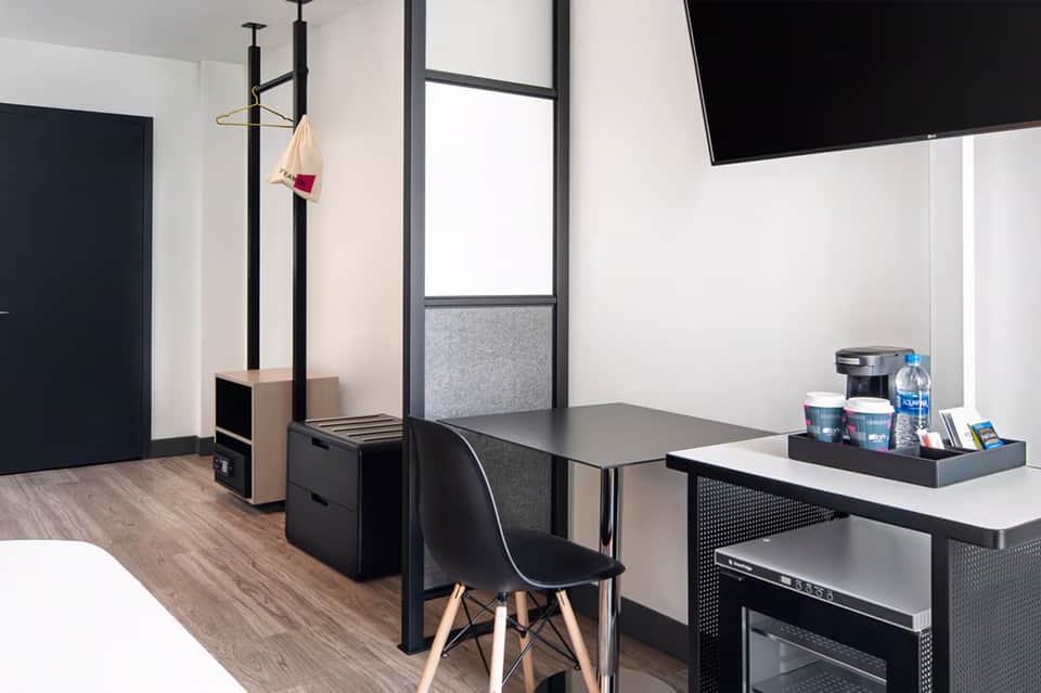 Modern office pod workspace with desk, chair, storage, and wall-mounted TV in contemporary setting