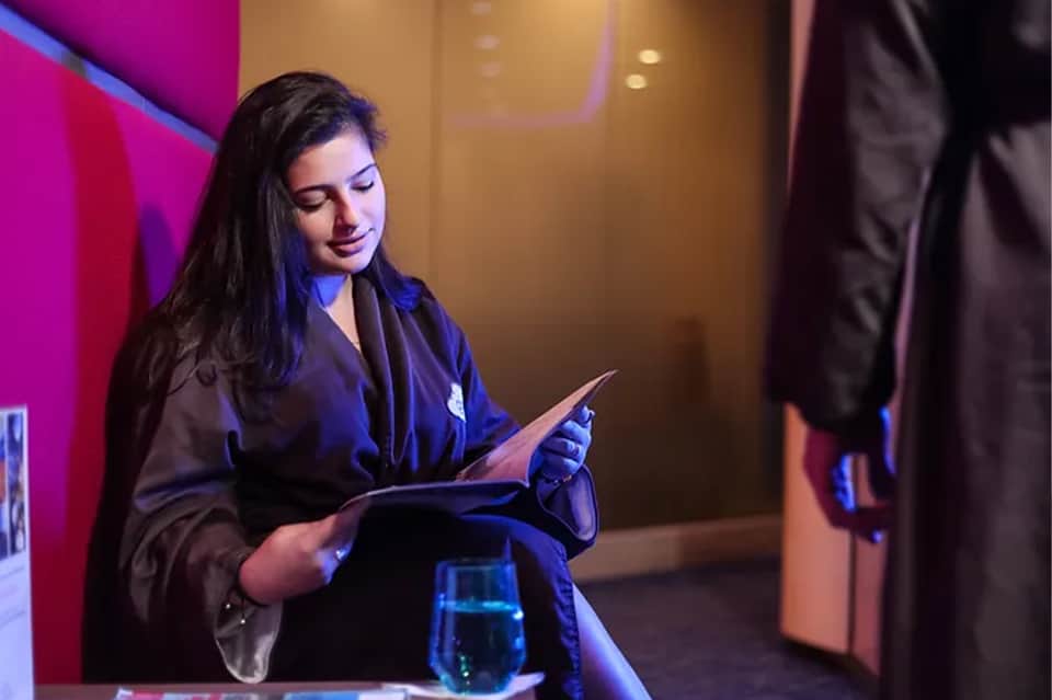 Female hotel staff member in dark blazer reviewing documents in modern lounge area