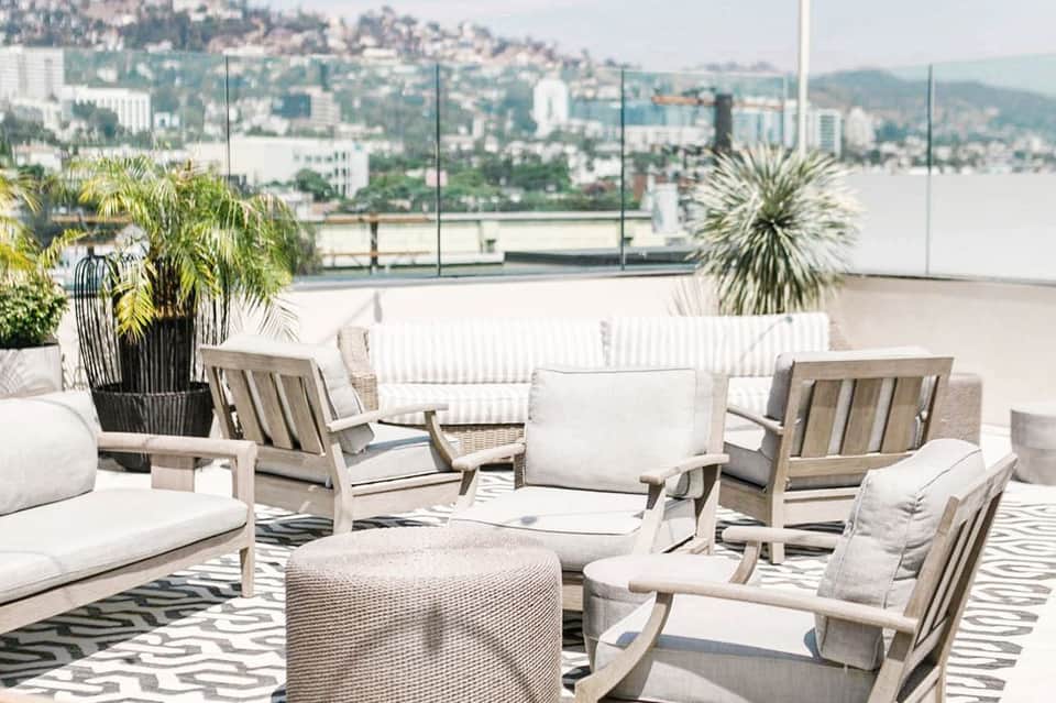 Modern rooftop lounge with neutral furniture, city skyline views, and potted plants