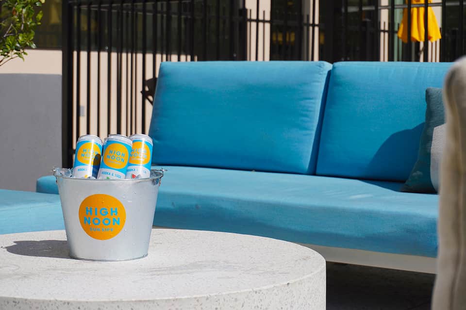Poolside lounge area with blue cushioned seating, concrete table, and black railing