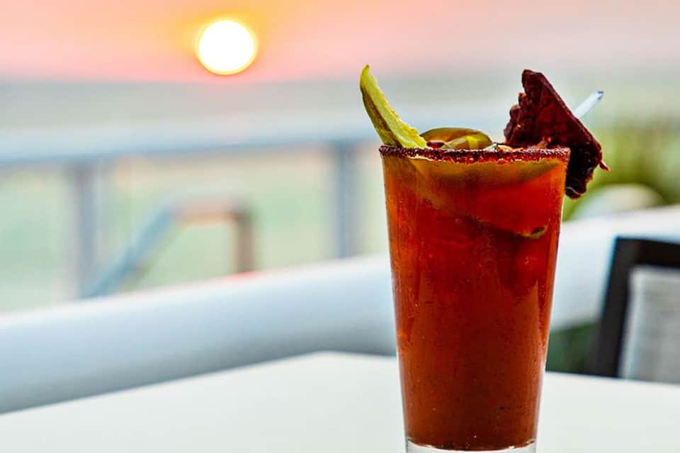 Sunset cocktail with lime garnish and dark red drink by ocean view at beachfront resort