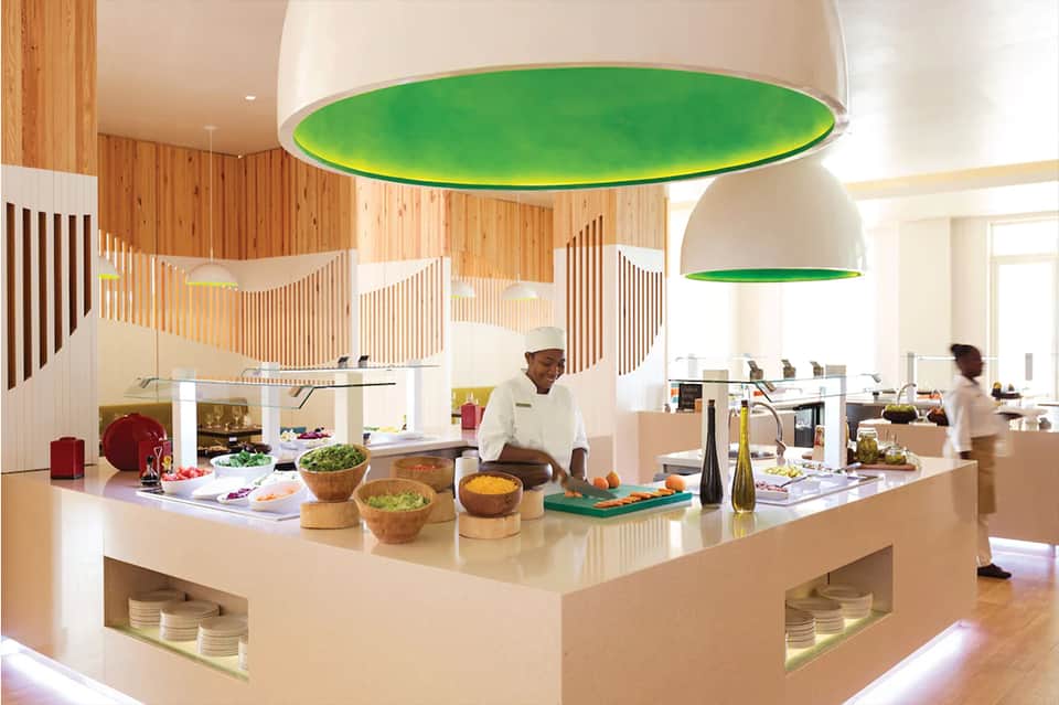 Modern open kitchen with chef preparing food under green pendant lights