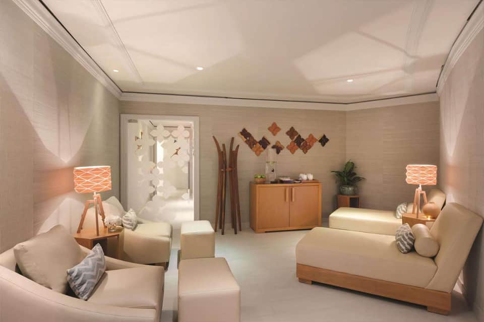 Spa relaxation room with cream seating, wooden accents, and warm ambient lighting