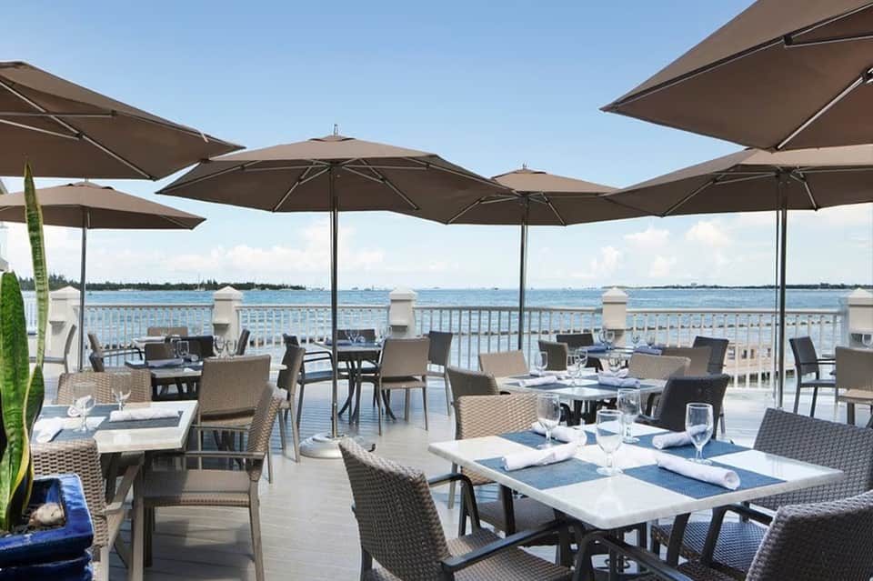 Waterfront dining terrace with tables, umbrellas, and bay views at an upscale restaurant
