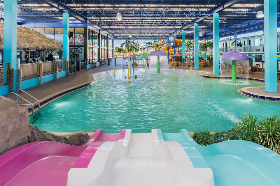 Indoor water park with turquoise pools, colorful water slides, and tropical-themed decorations