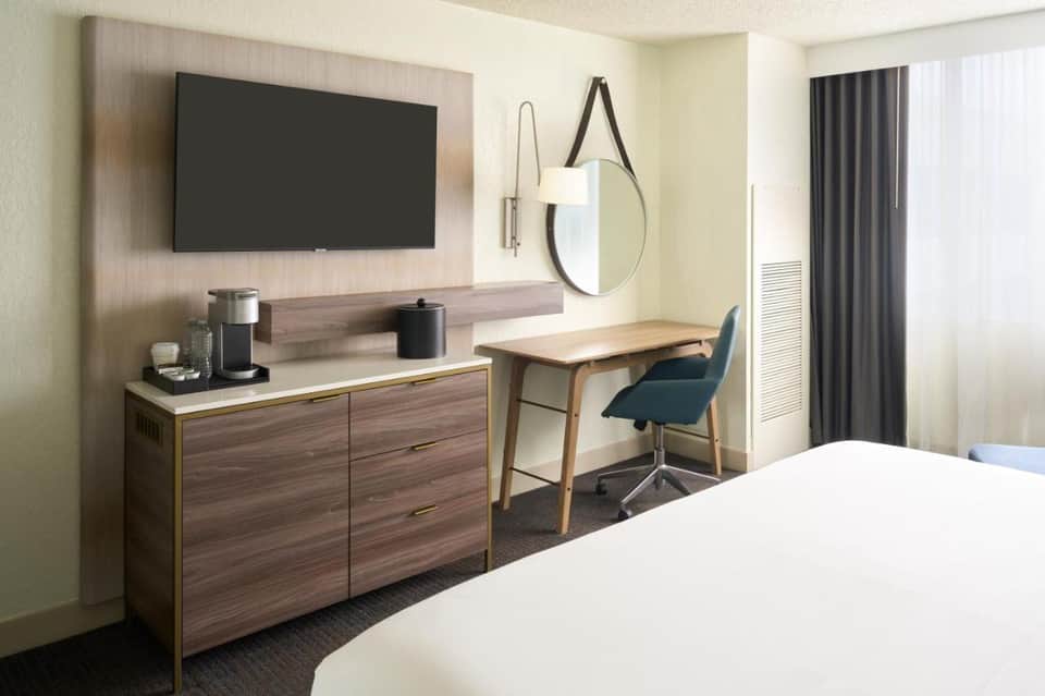 Modern hotel room with television, desk, work chair, and contemporary furnishings