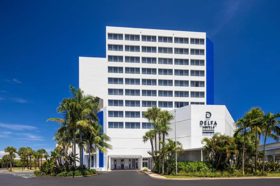 White Delta Hotels building exterior with palm trees and blue sky