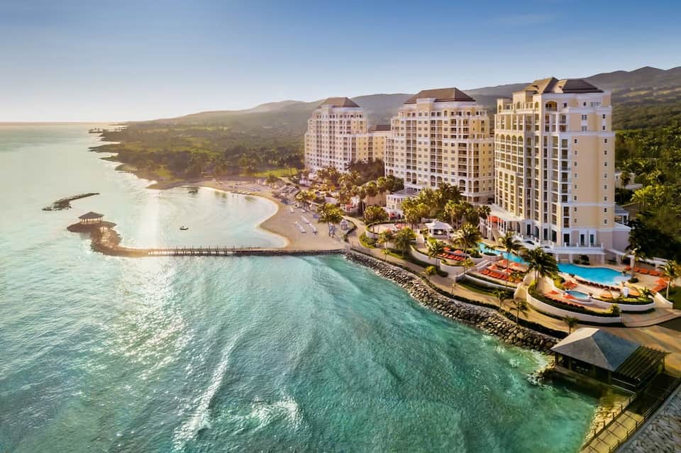 Beachfront resort with multi-story buildings overlooking turquoise ocean and sandy beach