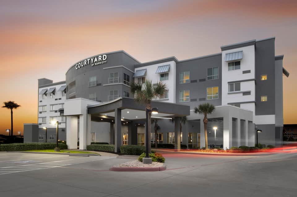 Modern Courtyard hotel exterior at dusk with palm trees and contemporary architecture