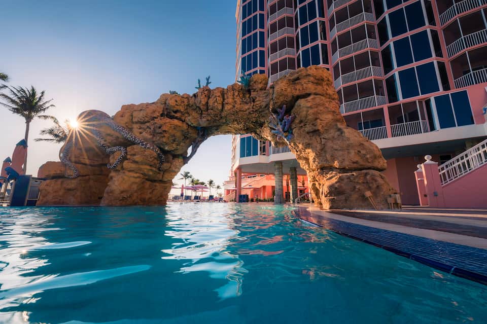Unique sculptural rock formation in resort swimming pool with high-rise buildings in background