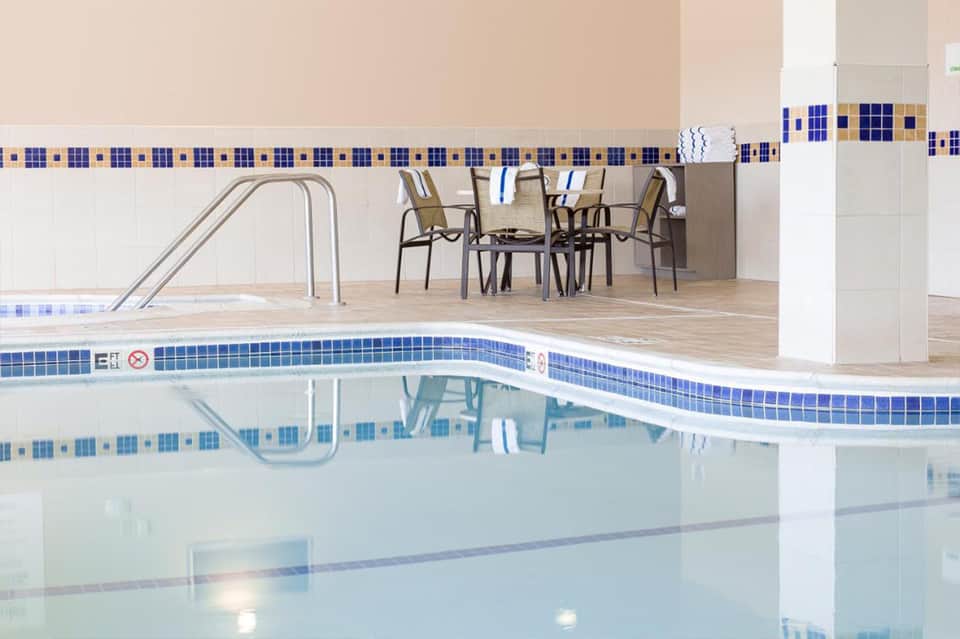 Indoor pool with blue tile border, lounge chairs, and modern seating area