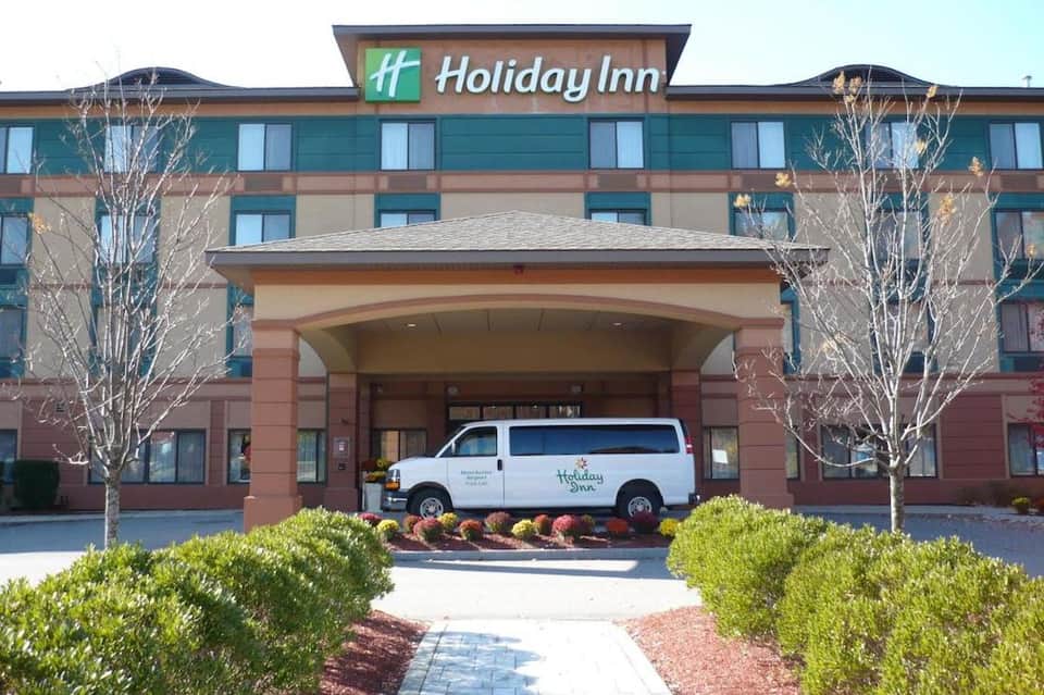 Holiday Inn hotel exterior with entrance, shuttle van, and landscaped grounds