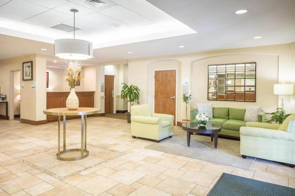 Hotel lobby with cream-colored seating, green accent chairs, and modern lighting