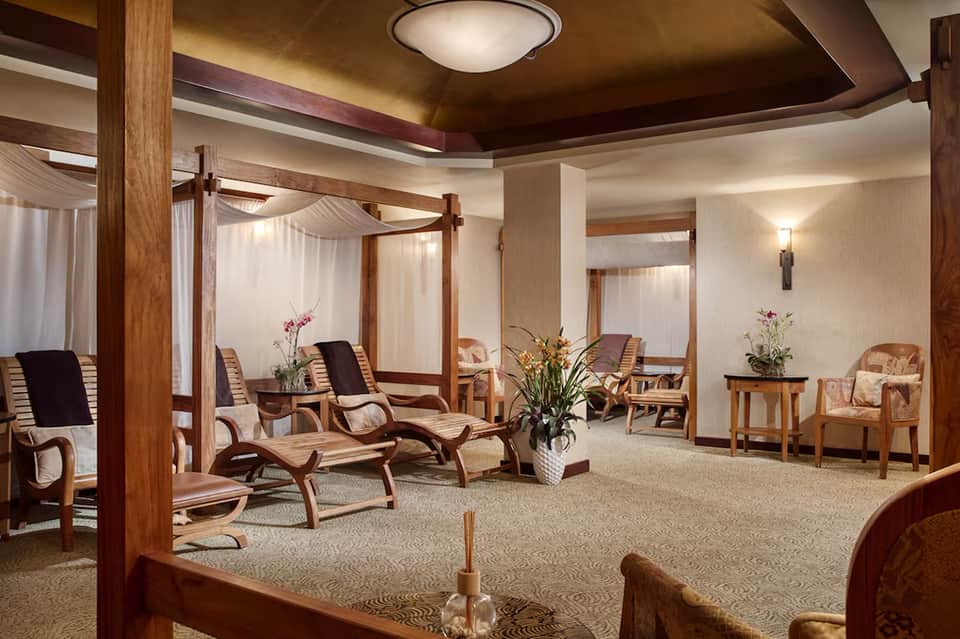 Spa relaxation room with wooden four-poster beds and lounge chairs
