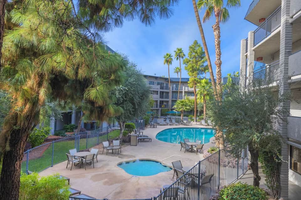 Resort courtyard with two pools, lounge chairs, palm trees, and multi-story building