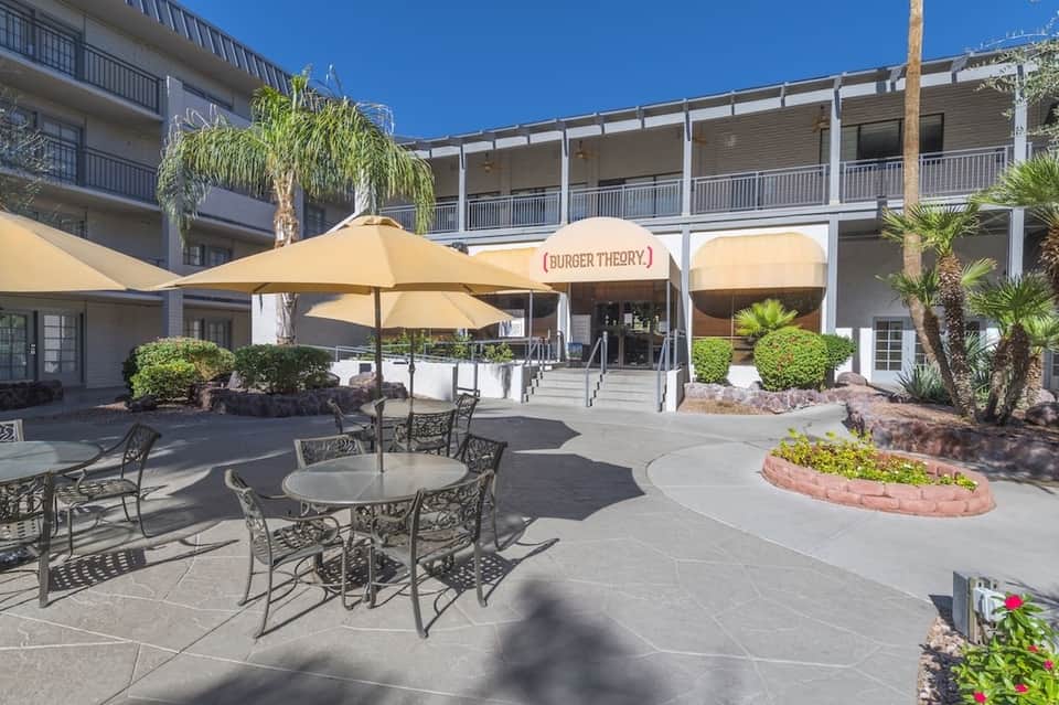 Hotel courtyard with outdoor dining area, umbrella-covered tables, and Burger Theory restaurant