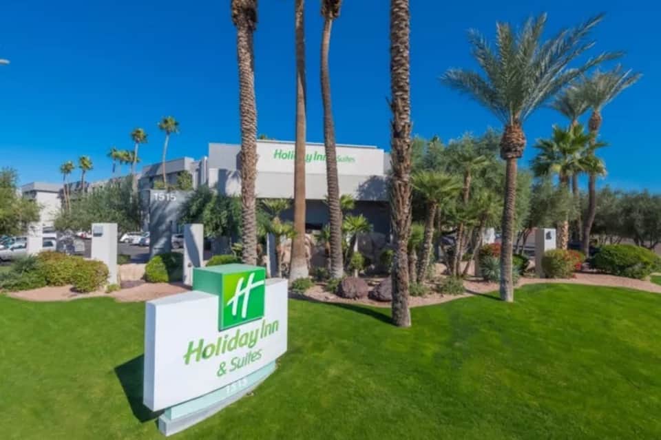 Holiday Inn & Suites hotel exterior with palm trees and manicured lawn landscape