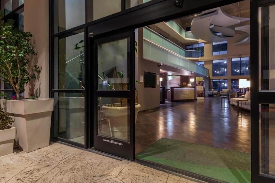 Modern hotel lobby entrance with black framed glass doors and wooden flooring
