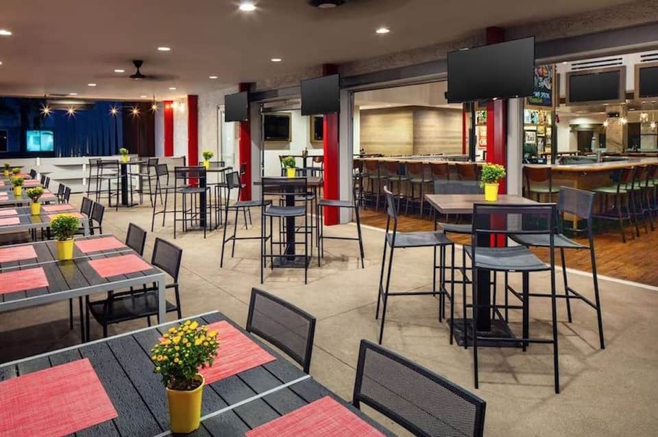 Spacious hotel event space with high ceilings, red and blue accents, and multiple dining areas