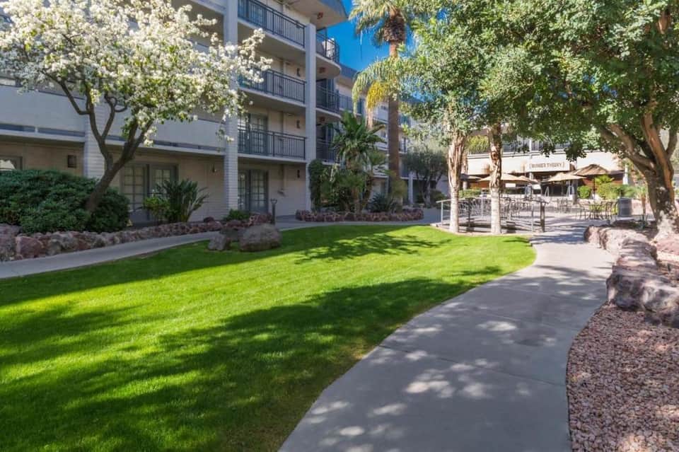 Hotel courtyard with manicured lawn, flowering trees, and residential buildings
