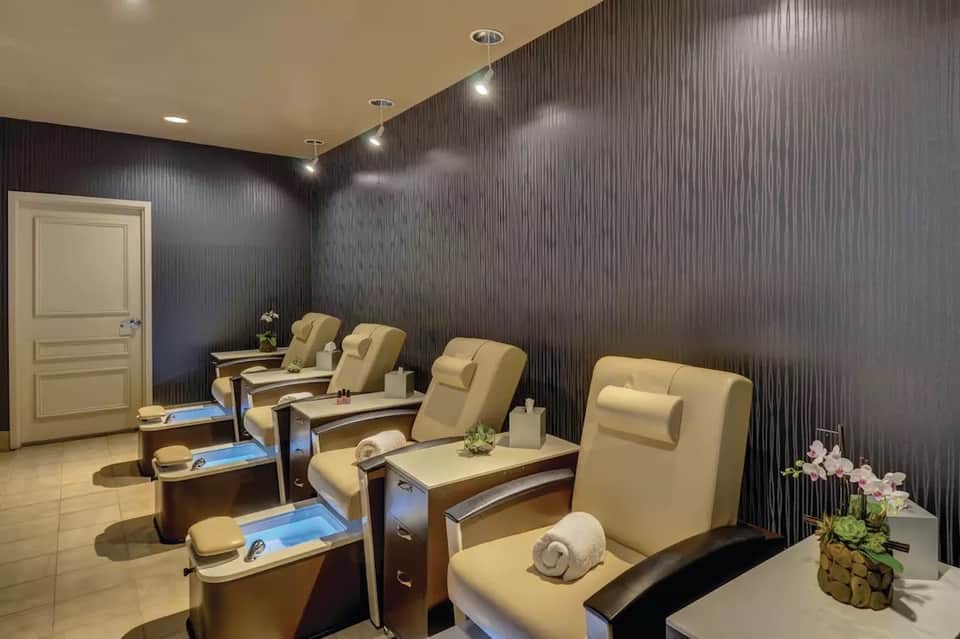 Elegant spa pedicure room with cream-colored chairs and dark wood-textured walls