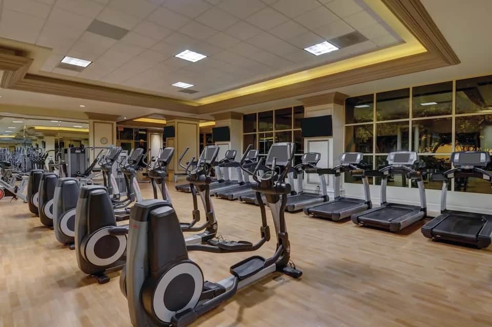 Spacious fitness center with rows of stationary bikes, treadmills, and exercise equipment under bright ceiling lights