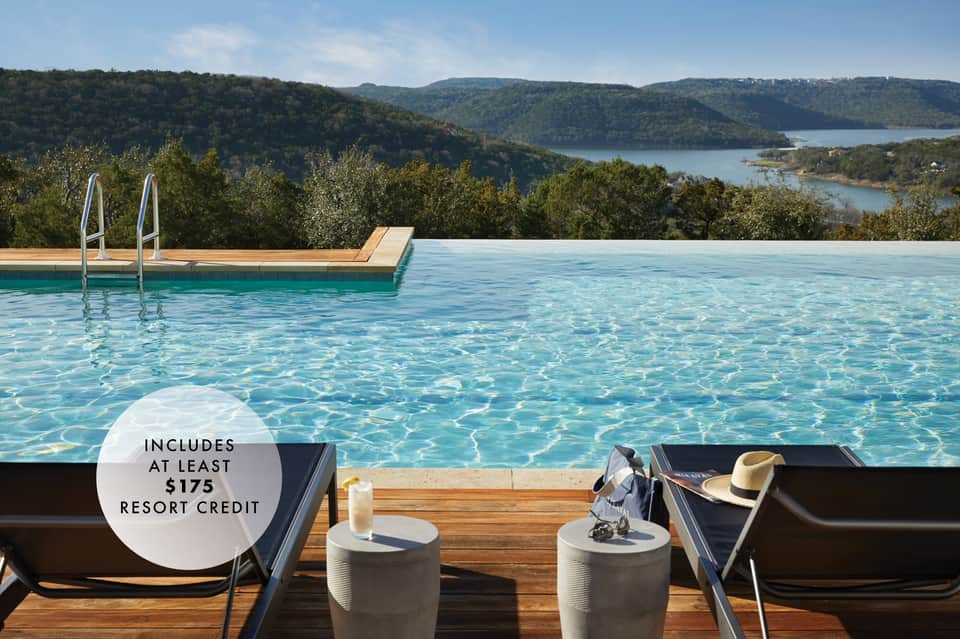 Infinity pool overlooking forested hills and lake with lounge chairs and $175 resort credit
