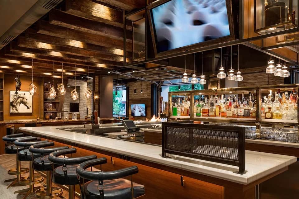 Upscale bar with wood ceiling, pendant lights, and full liquor display behind counter