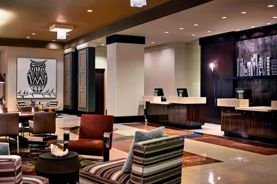 Contemporary hotel lobby with geometric artwork, dual reception desks, and striped seating