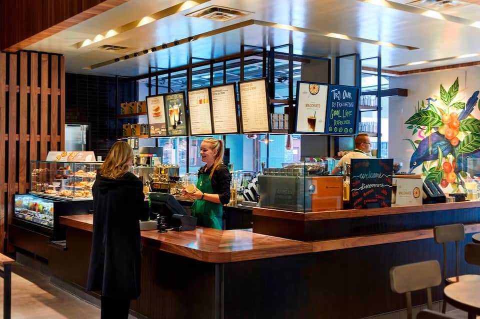 Contemporary coffee shop interior with modern counter, menu boards, barista staff, and bright lighting