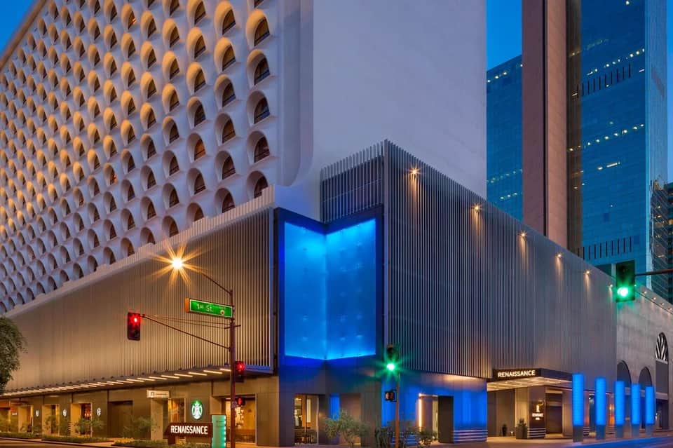 Contemporary hotel building at night with illuminated blue entrance and geometric patterned white facade