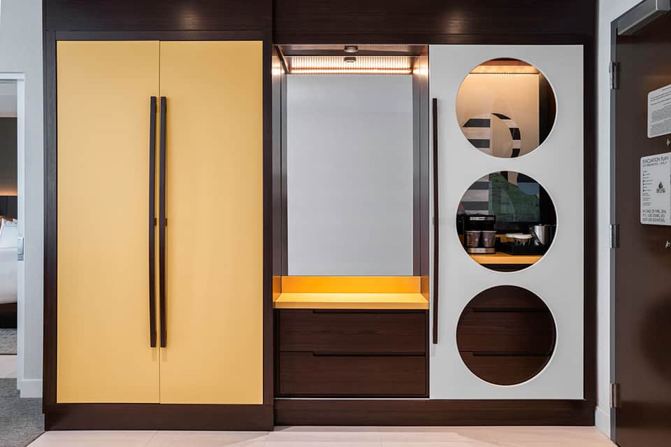 Modern display cabinet with yellow doors, illuminated shelving, and circular mirror cutouts