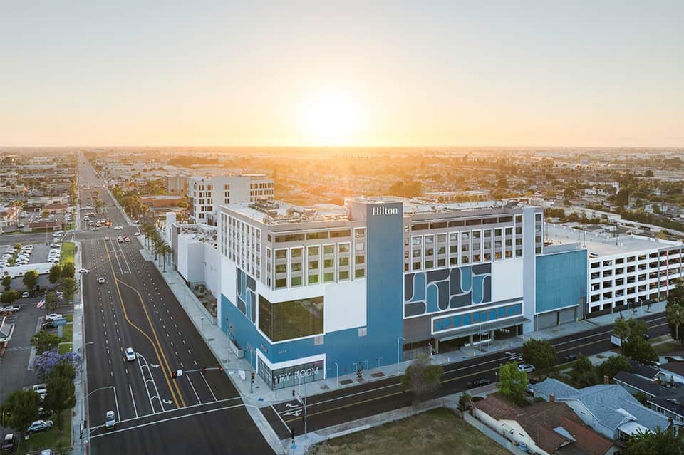 Modern Hilton hotel exterior at sunset with multi-story building and street view