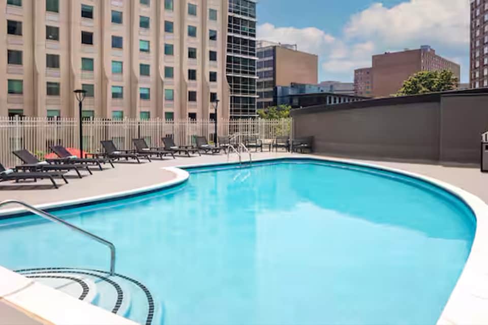 Resort rooftop pool with lounge chairs and urban skyline views