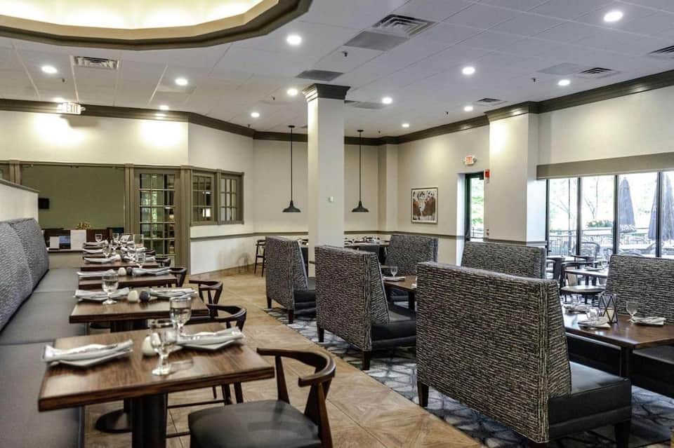Fine dining restaurant interior with booth seating, pendant lighting, and lake view windows
