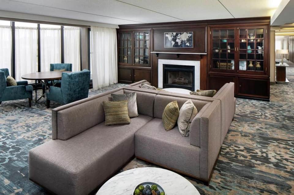 Luxury suite living room with gray sectional sofa, fireplace, wood cabinetry, and elegant furnishings