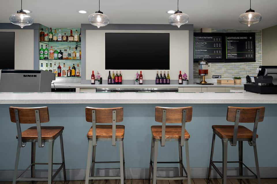 Modern bar interior with wooden stools, liquor bottles, and menu boards